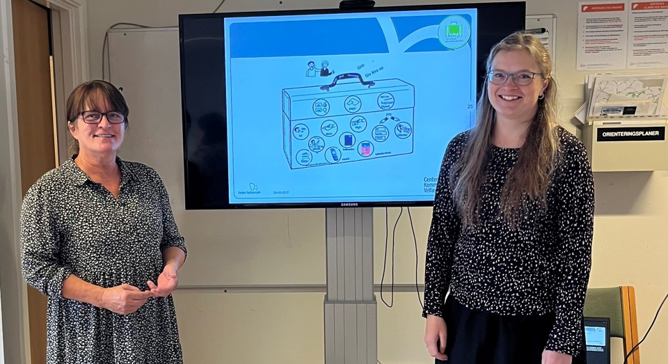 Underviserne Camilla og Sanne står foran skærm med undervisningsmodel