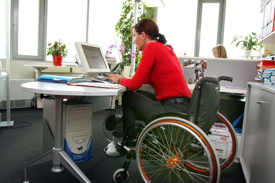 Kvinde i kørestol på arbejde ved en computer