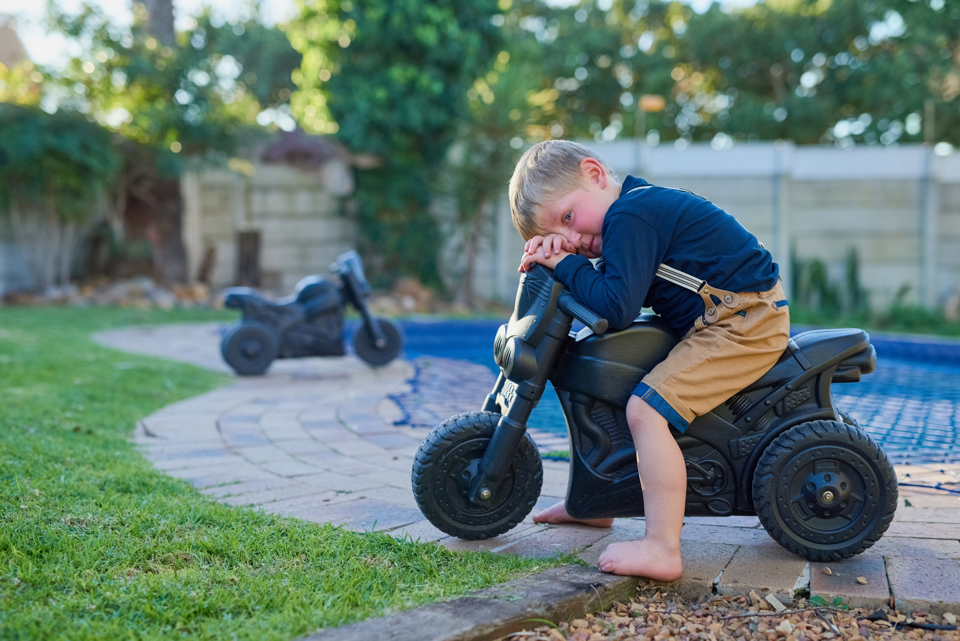 lille dreng på legetøjs motorcykel sidder og er ked af det