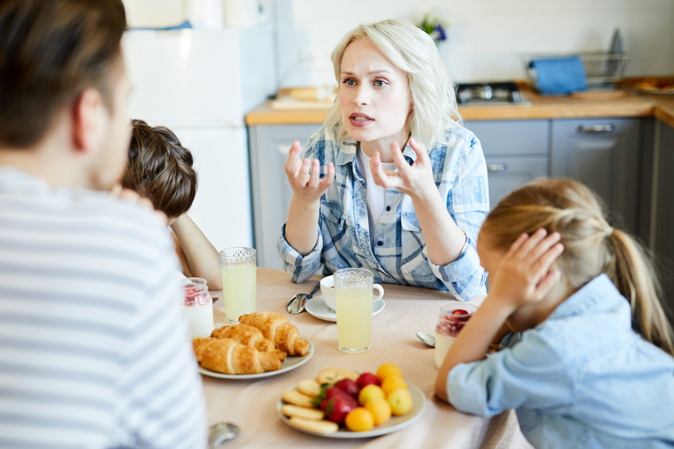 Kvinde skændes med sin mand, mens to børn holder sig for ørerne