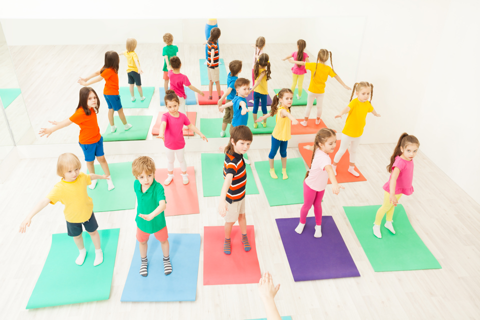 en gruppe mindre børn dyrker yoga på yogamåtter