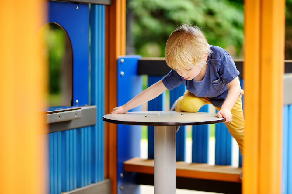 Lille dreng leger alene på en legeplads