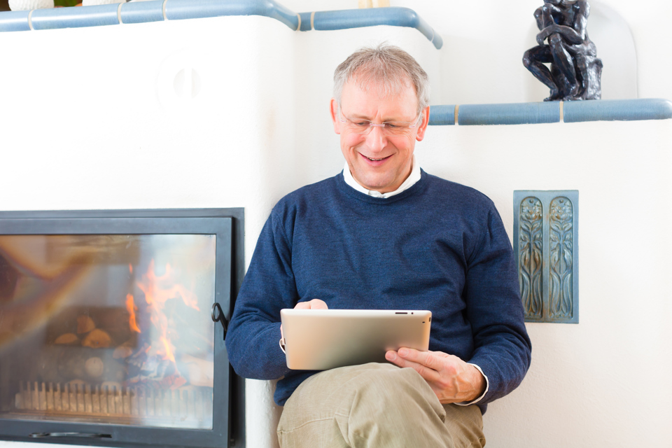 mand sidder og kigger på tablet, mens han smiler